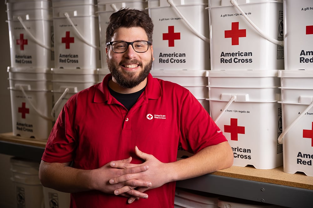 UNO emergency management graduate Jonathan Kiper stands in front of American Red Cross supplies